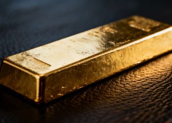 Un lingot d'or brillant sur une surface sombre.