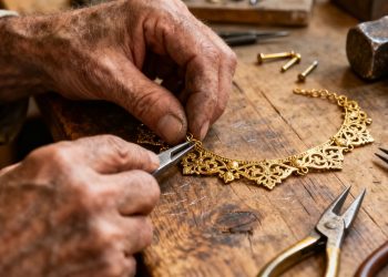 Ein Handwerker repariert mit Werkzeugen eine mittelalterliche Halskette.