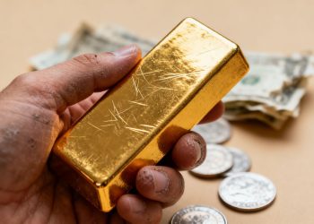Main d'or tenant une barre d'or brillante dans un portefeuille diversifié.