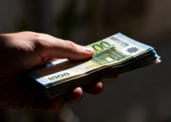 Main d'une personne tenant des billets en euros.