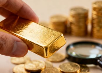 Main d'or comparant des lingots d'or et des pièces.