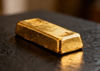 Barra de oro brillante sobre fondo oscuro.