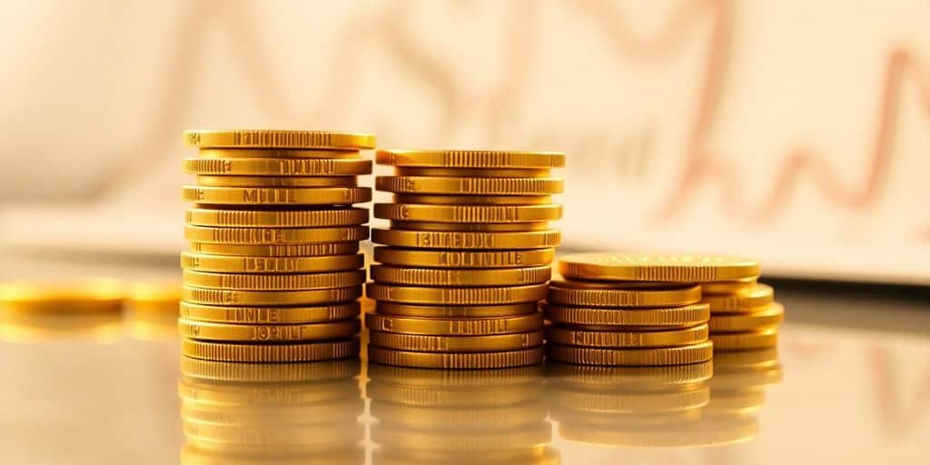Pièces d'or empilées brillantes sur surface réfléchissante.