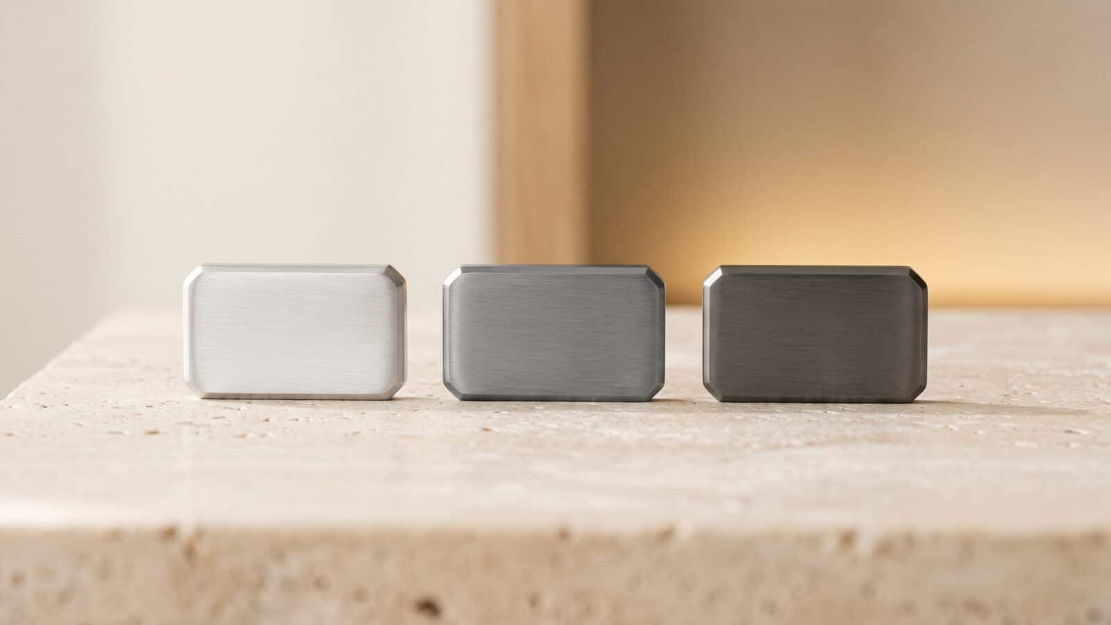 Trois petits lingots alignés, argent, platine et palladium, sur une pierre claire